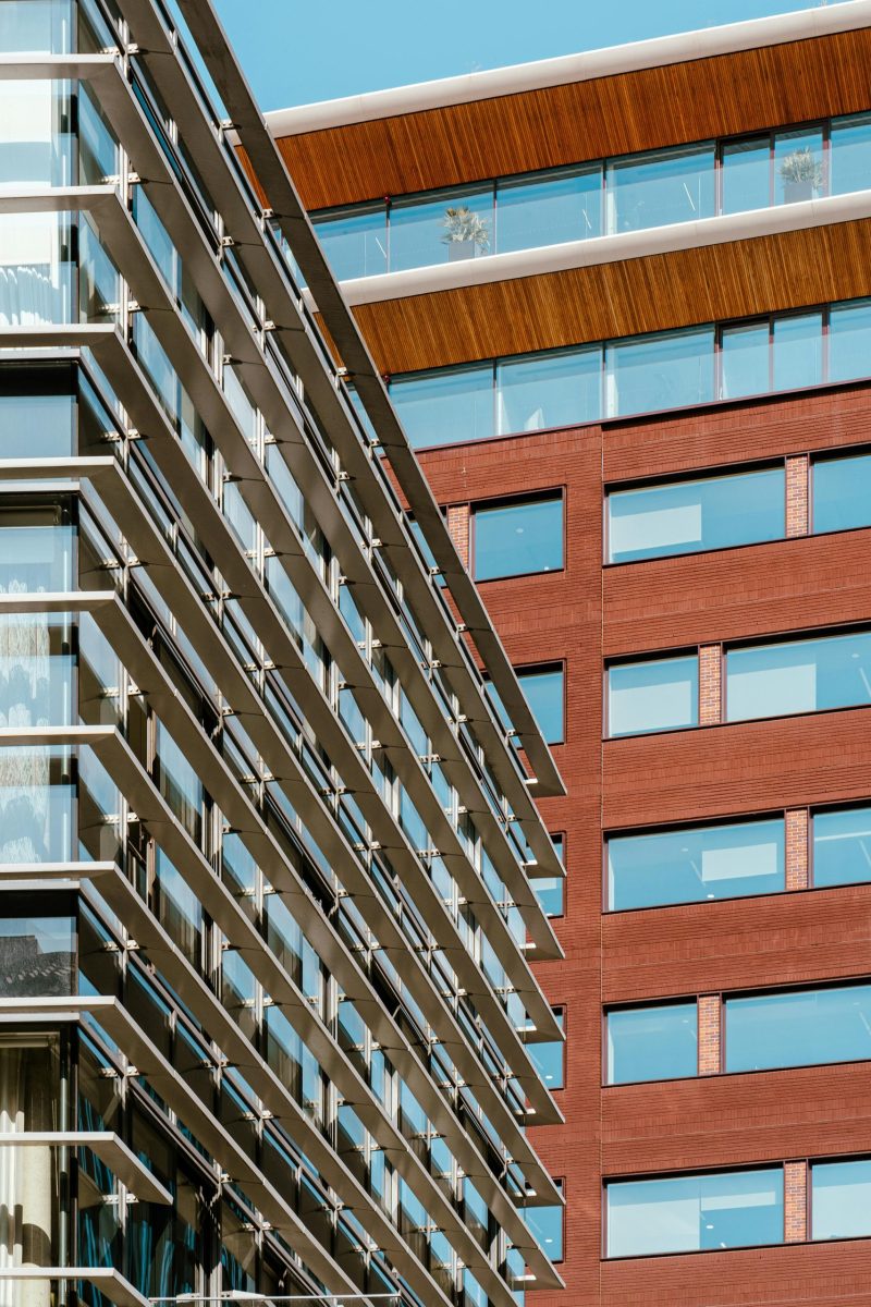 Low angle shot of modern urban buildings with glass windows and wooden accents.