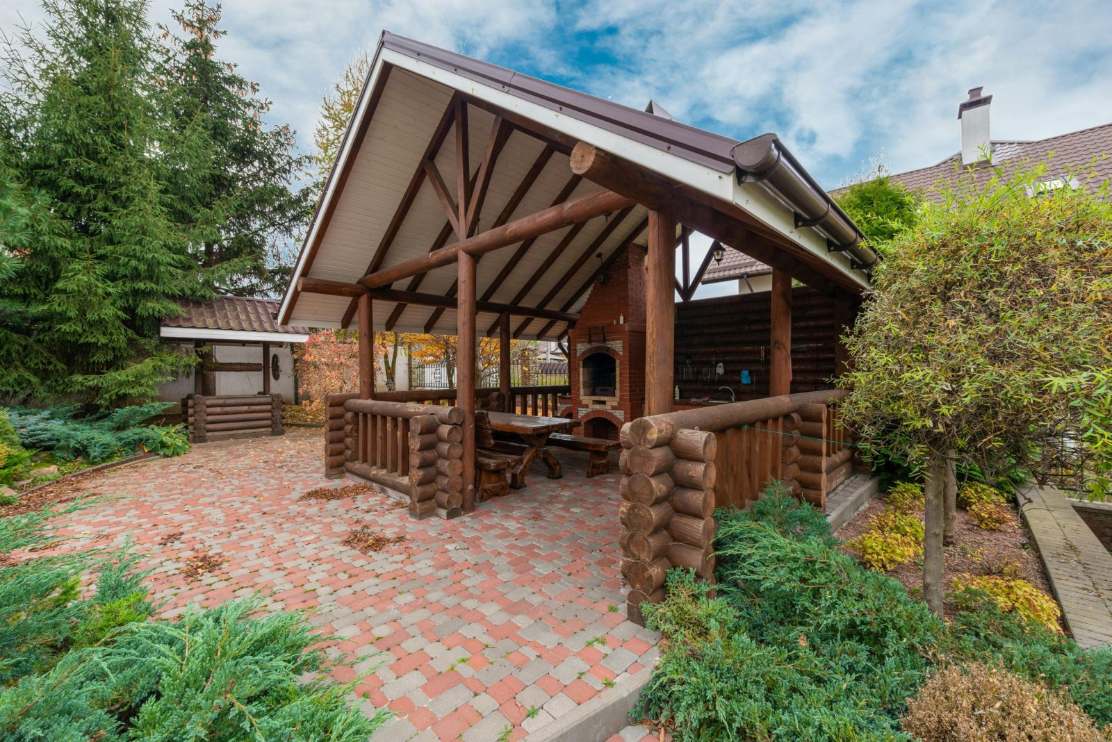 Rustic log pavilion in a garden setting, perfect for outdoor gatherings.